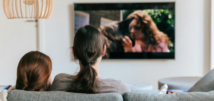 Ilustrační fotografie dvou diváků sledujících televizi z pohovky