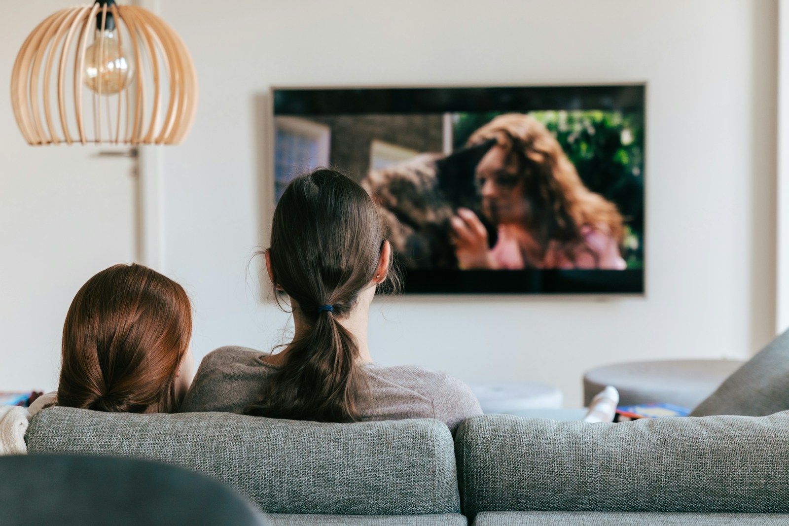 Ilustrační fotografie dvou diváků sledujících televizi z pohovky